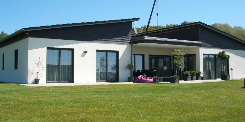 Moderner Bungalow mit Pultdach und gro&szlig;z&uuml;giger &uuml;berdachter Terrasse vor weiter Wiese