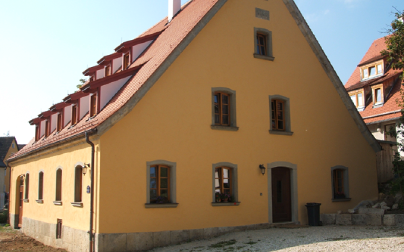 Saniertes Bauernhaus mit ockergelbem Putz und neuem Ziegeldach mit drei Reihen Gauben